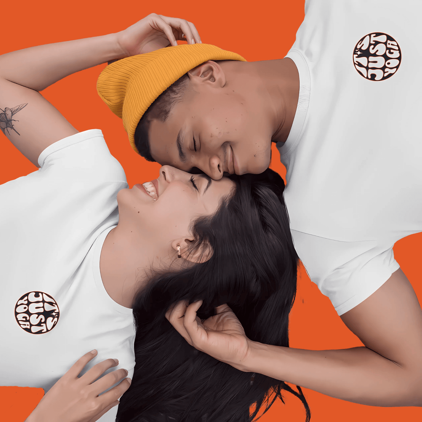 Happy couple wearing "It's Just Yoga" unisex tees, enjoying a playful moment on an orange background.